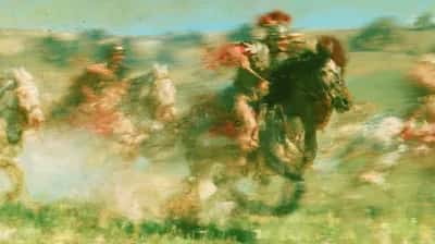 Horse and rider galloping through dusty green landscape, motion blur, earthy tones