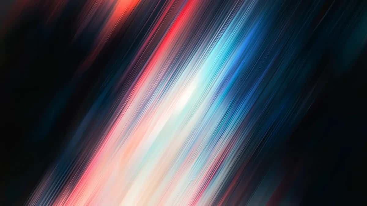 Abstract diagonal light streaks blending red, pink, white, and blue tones on dark background