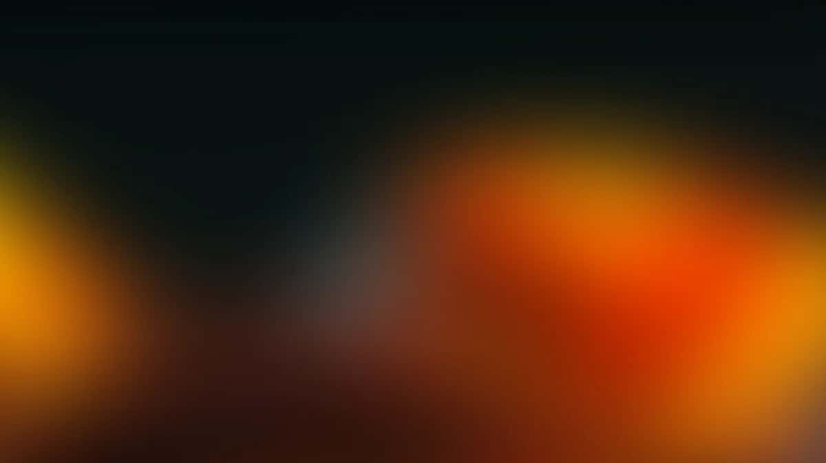 Abstract gradient background with warm orange and yellow tones fading to dark charcoal