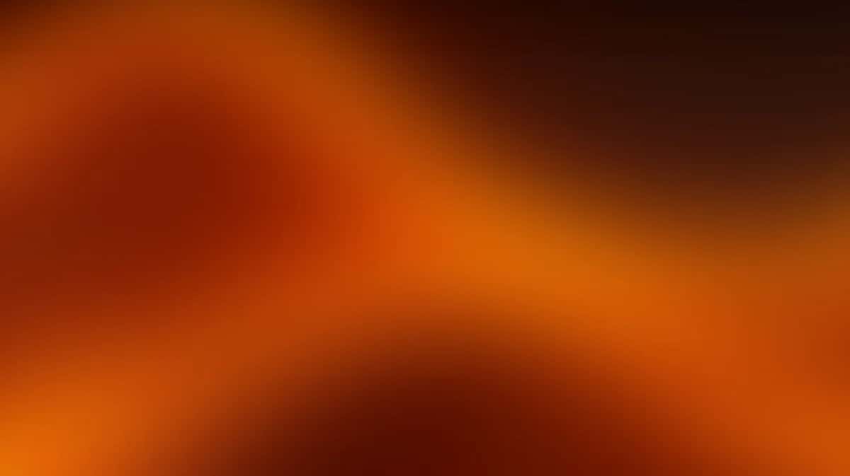 Abstract warm gradient background transitioning from deep brown to bright orange with soft blur