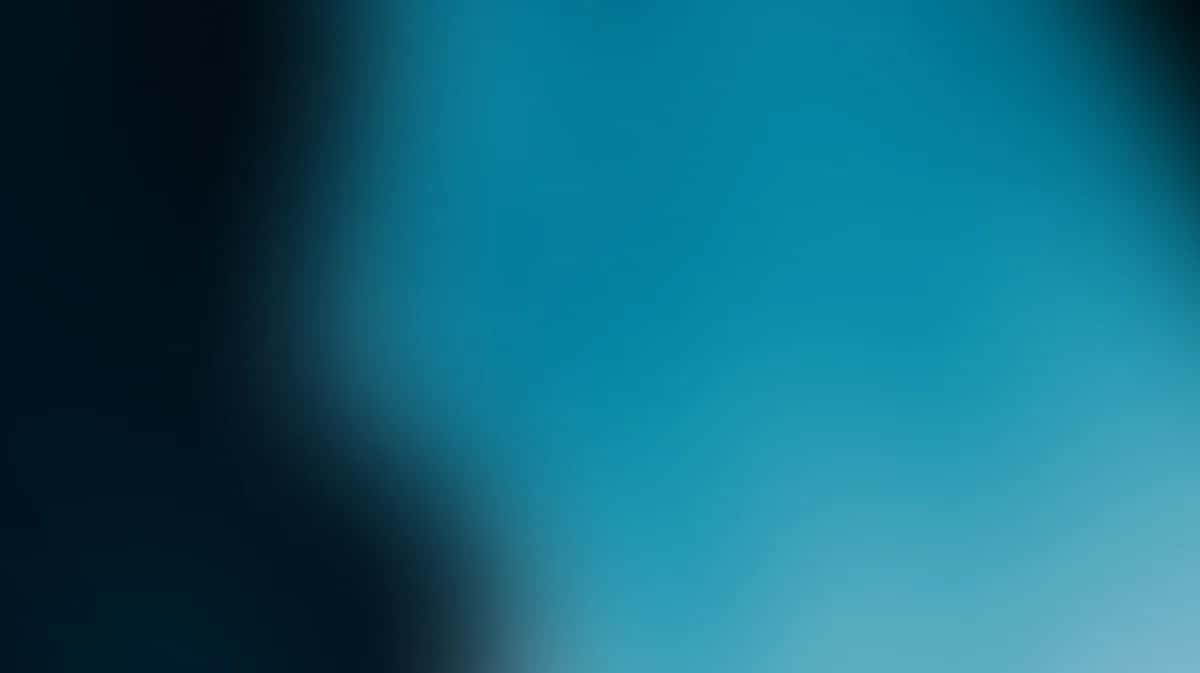 Abstract teal blue gradient background with soft light leak effect transitioning from dark to bright