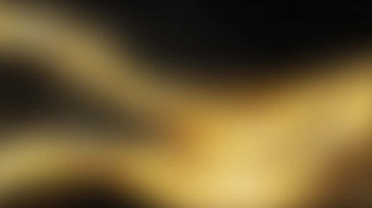Blurred golden and black gradient background with soft diagonal light rays and bokeh effect