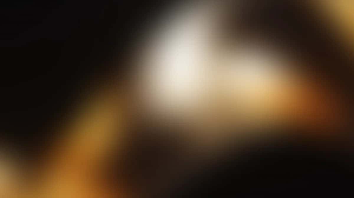 Abstract blurred gradient with warm golden amber tones and dark black areas, soft bokeh lighting effect