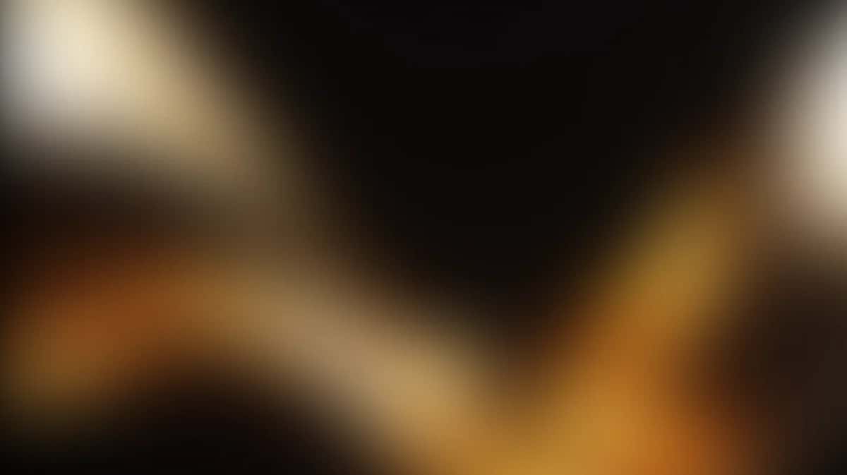Abstract blurred gradient background with warm amber, black, and cream tones blending softly
