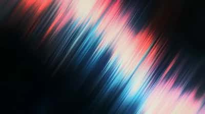 Diagonal blurred light trails in red, pink, cyan and white on black
