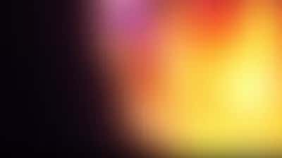 Hazy gradient glow shifting from dark plum to magenta, orange and bright yellow