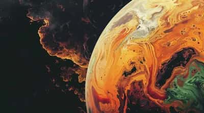 Surreal marbled planet in amber and cream with green pools beside smoky cosmos