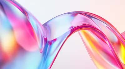 Translucent glassy ribbon refracting rainbow pink, blue, yellow and red on pale background