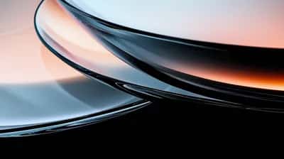 Curved glassy black surfaces lit by peach and pale blue gradient glow