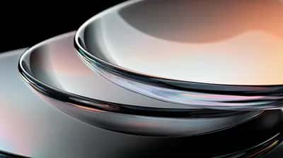 Stacked chrome glass discs with iridescent reflections on black background