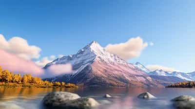 Snow-capped pink-tinged peak above a calm lake, golden autumn trees and clear blue sky