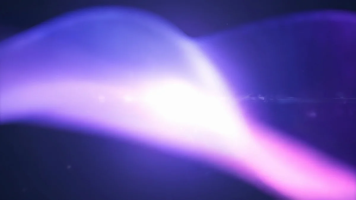 Abstract purple and pink light rays flowing across dark blue blurred background