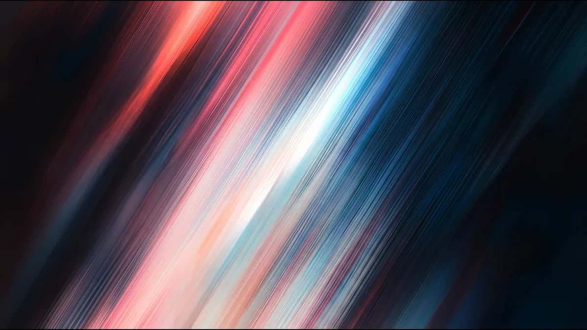 Diagonal motion-blur light streaks in crimson, white and cyan on near-black